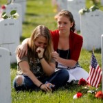 Heidi Heming, 27 yrs-old, left, of Chattanooga, Tenn.  is comforted by volunteer Marina Clifford, 12 yrs-old, while visiting a loved one's gravesite at Section 60 on Memorial Day at Arlington National Cemetery in Arlington, Virginia, Monday, May 27, 2013.  Iraq and Afghanistan war veterans are buried in Section 60. (AP Photo/Molly Riley)